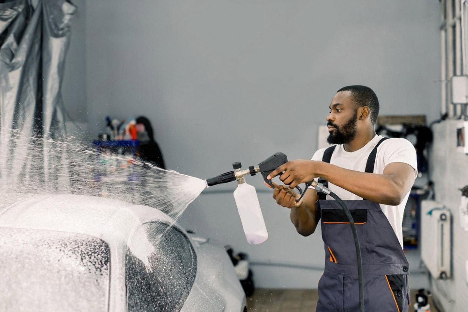 Detailer applying foam wash to a car in a Dubai detailing bay to protect paint from sun and sand