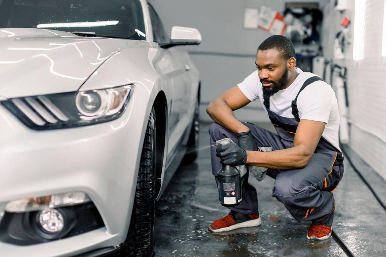 Detailer finishing a silver sports car with interior spray, preserving showroom condition for resale