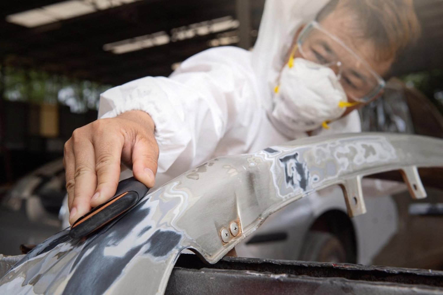 Technician sanding and prepping a car panel for paint correction during a detailing session in the UAE